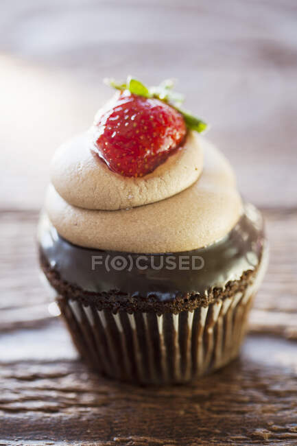Schokoladen-Cupcake mit Schokocreme und Erdbeere oben drauf — Stockfoto