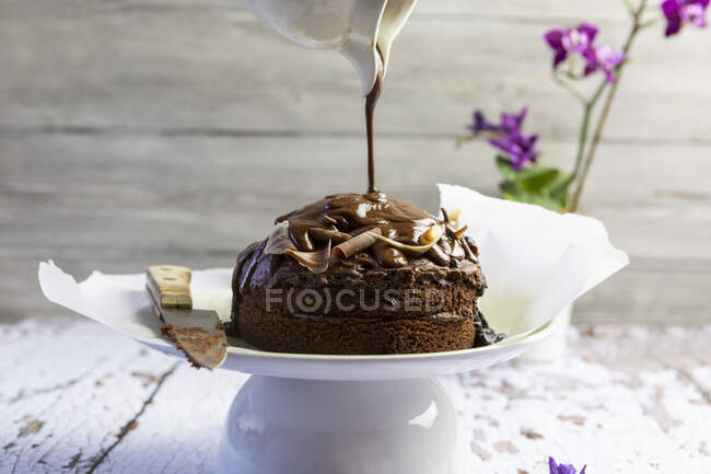 Chocolate cake with chocolate sauce pouring on top of it — Stock Photo