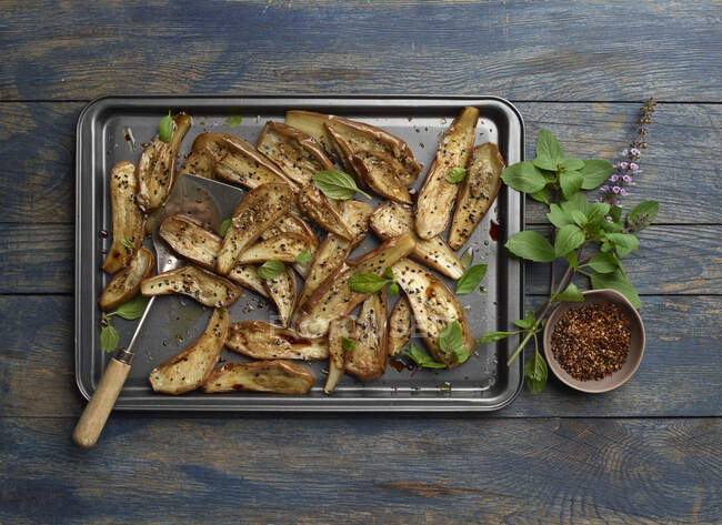 Roasted eggplant on baking sheet with spices and basil - foto de stock