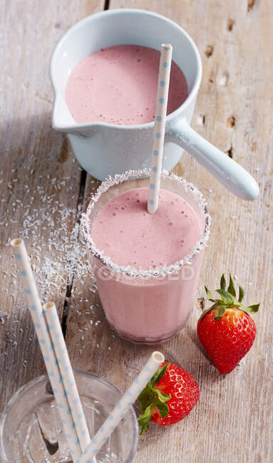 Creamy strawberry and coconut shake with straws and fresh strawberries — Stock Photo