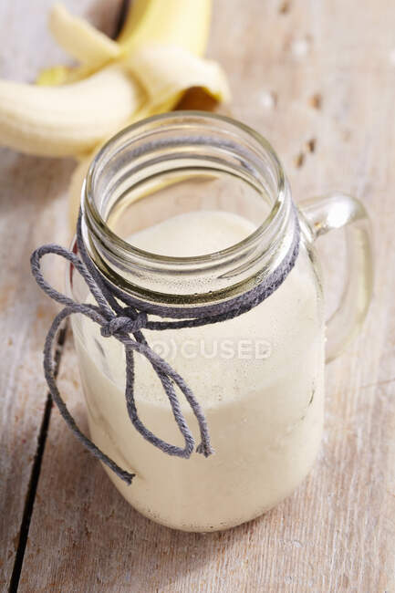 Un milkshake à la banane dans un bocal à vis avec sirop et glace à la vanille — Photo de stock