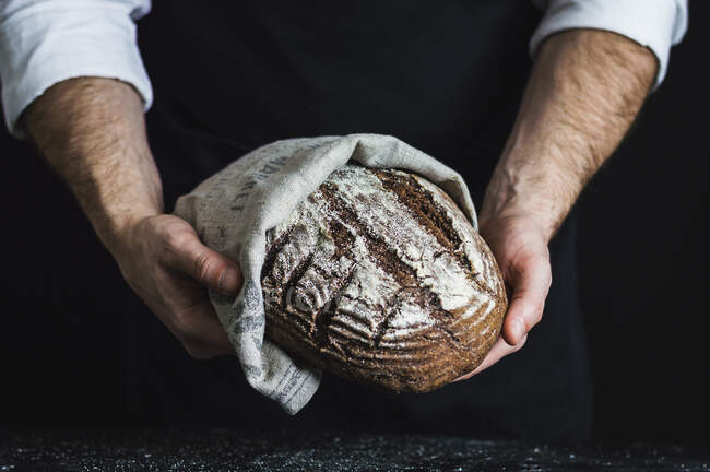 Man holding a spelt and wholewheat bread made with aronia (chokeberry) powder — Fotografia de Stock