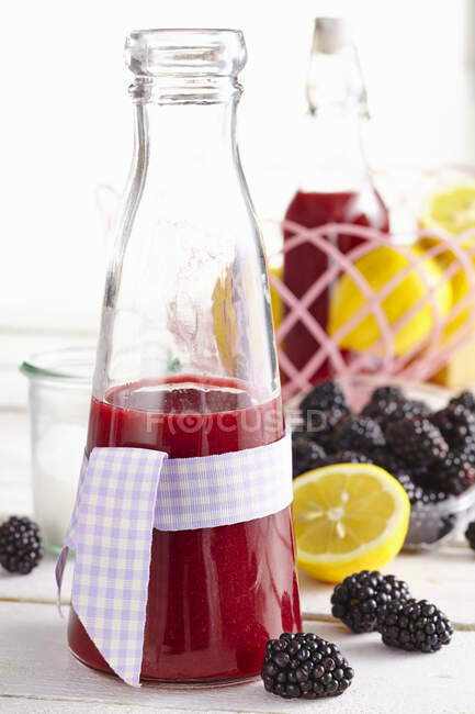 Bottle of fruity blackberry liqueur with bow — Stock Photo
