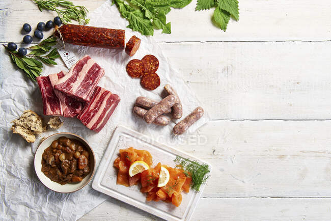 Mixture of raw meat, cured sausage, smoked salmon, and beef stew with bread — Stock Photo