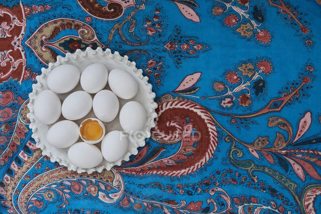 Белые яйца на голубой скатерти с цветочным узором — стоковое фото