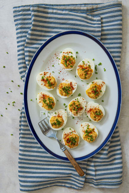 Huevos rellenos con yemas de huevo especiadas, pimentón y cebollino - foto de stock