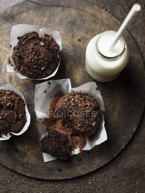Chocolate muffins with milk on brown background top view — Stock Photo