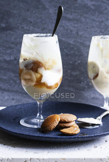 Glasses with banana pudding, sliced bananas, wafer cookies, vanilla pudding, whipped cream and caramel sauce — Photo de stock
