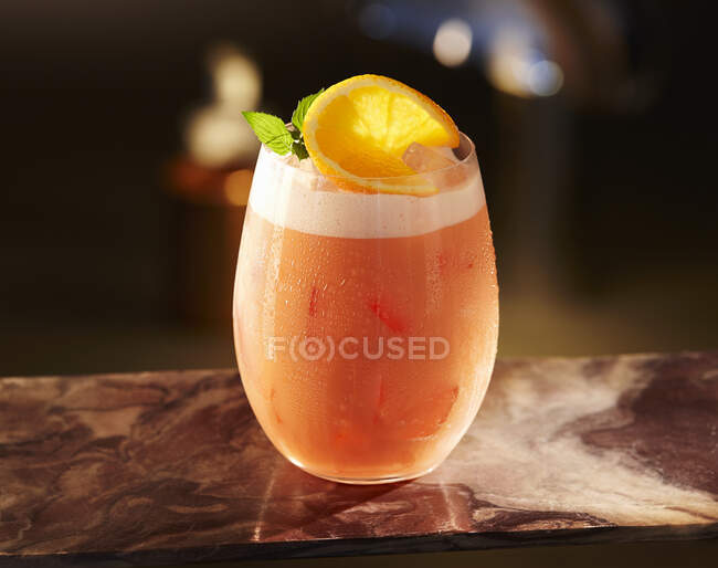 Стакан грейпфрутового коктейля с пеной, ломтиком лимона и листьями мяты — стоковое фото
