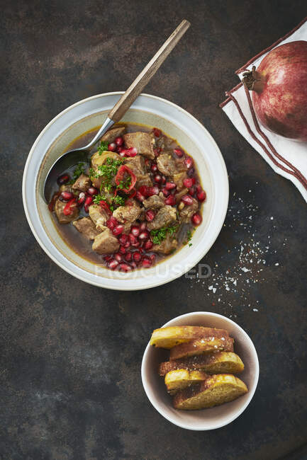Pork goulash with pomegranate seeds and potatoes — Stock Photo