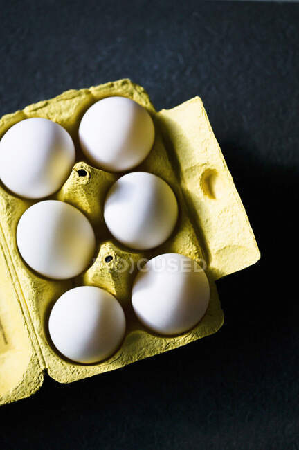 Яйця білих курей в жовтій коробці — стокове фото