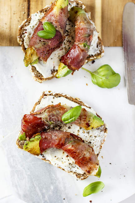 Bread topped with avocado, bacon and basil — Stock Photo