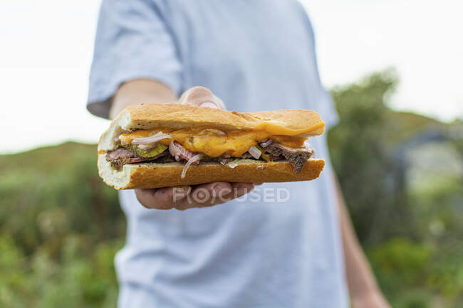 Un uomo che tiene in mano un panino con formaggio — Foto stock