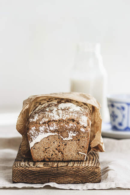 Rye bread on wooden board with milk bottle — Stock Photo