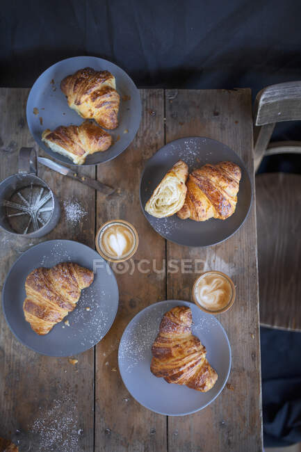 Croissant con cappuccini su un tavolo di legno rustico (vista dall'alto) — Foto stock