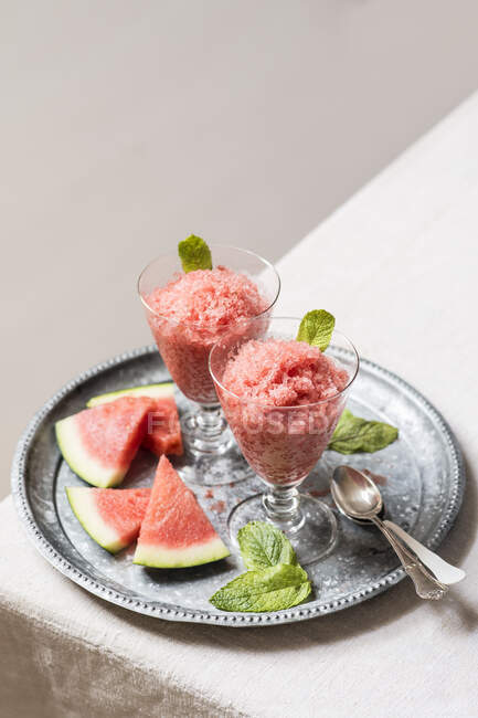 Köstliche Wassermelonen-Granita in Gläsern mit frischen Wassermelonenscheiben und Minzblättern auf Metalltablett — Stockfoto
