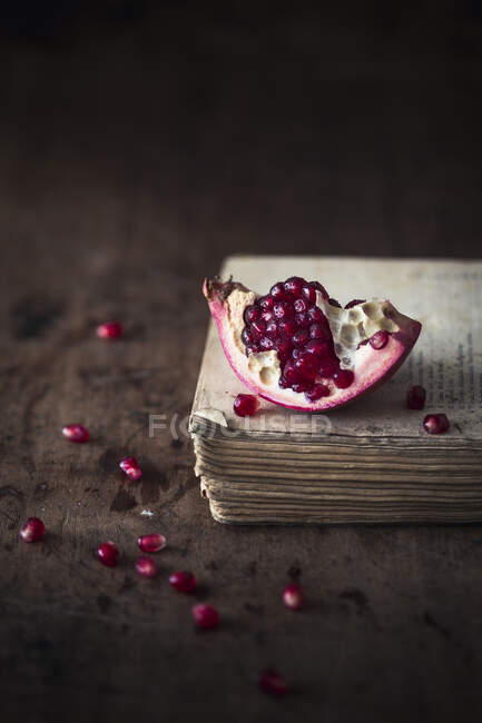 Piece of a fresh pomegranate on a wooden surface — Stock Photo