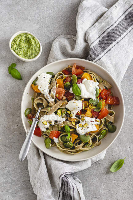 Tagliatelle with courgette, broad beans, tomatoes and pesto — Stock Photo