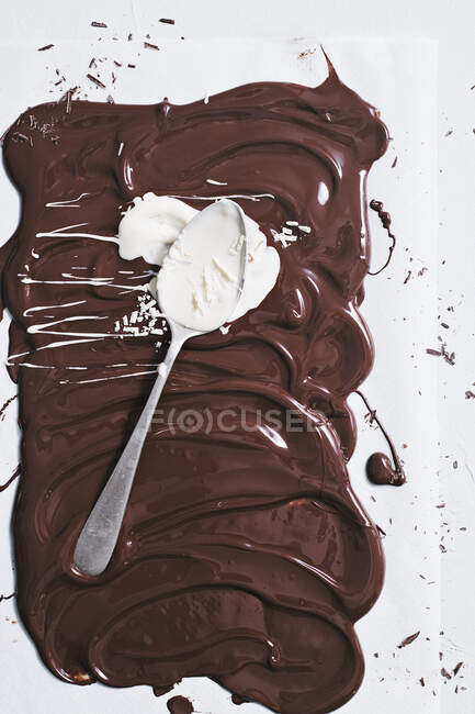 Liquid chocolate being spread with a spoonful of white chocolate — Stock Photo