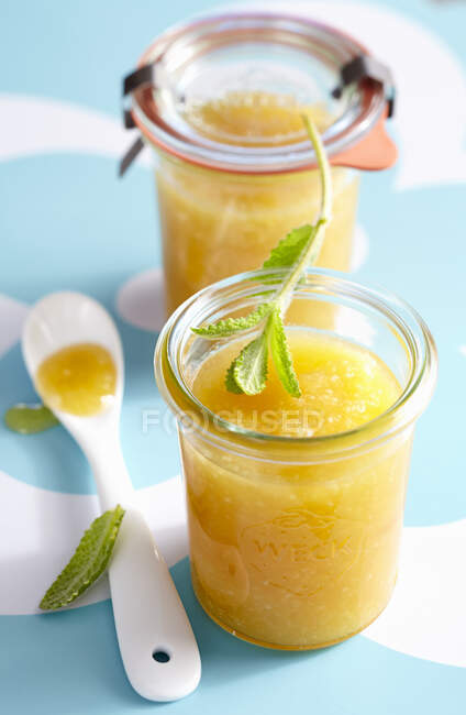 Jars of passionfruit jam with herbs and spoon — Stock Photo