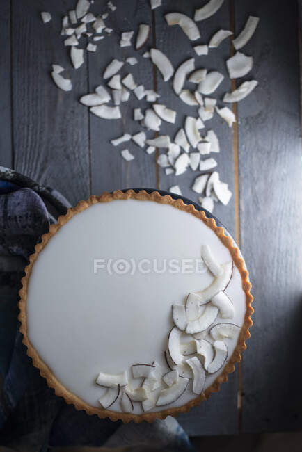 Torta de coco com pedaços de coco em uma superfície de madeira escura — Fotografia de Stock