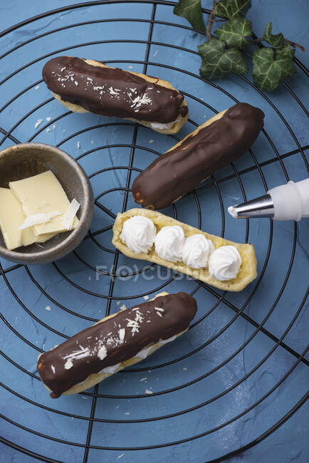 Chocolate eclairs being filled with whipped soya cream — Stock Photo