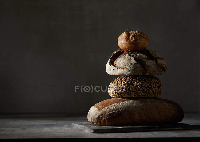 Drei verschiedene Brote und ein Brötchen, gestapelt — Stockfoto