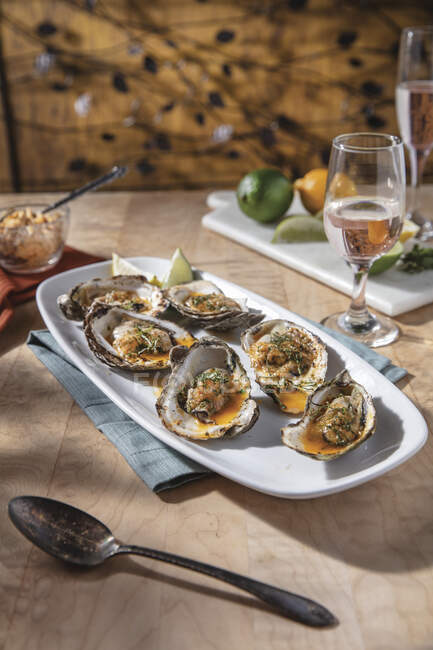 Smoked and Grilled Oysters on oblong with serving plate with rose in wine glass pairing — Stock Photo