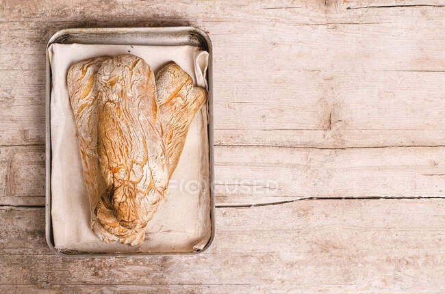 Ciabatta with paper in metal tin on wooden table — Stock Photo