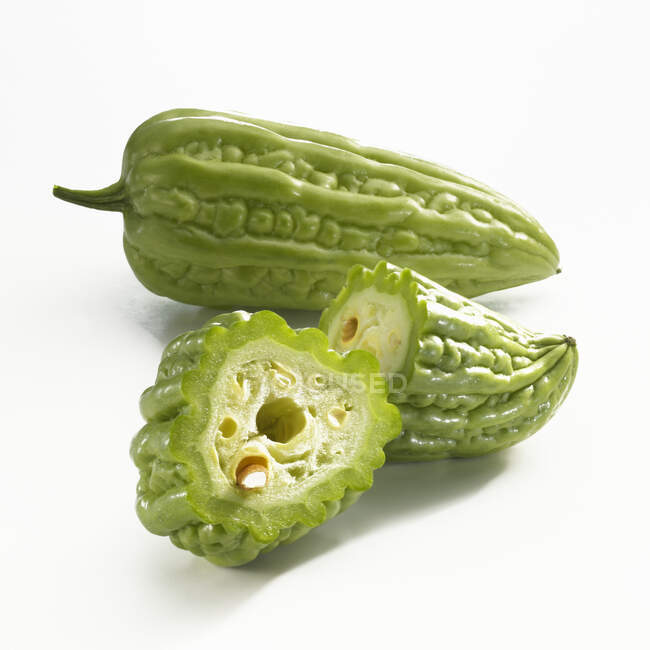 A whole and a halved bitter cucumber on a white background — Stock Photo