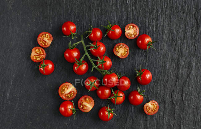 Fresh cherry tomato with drops of basil on a dark background — Stock Photo