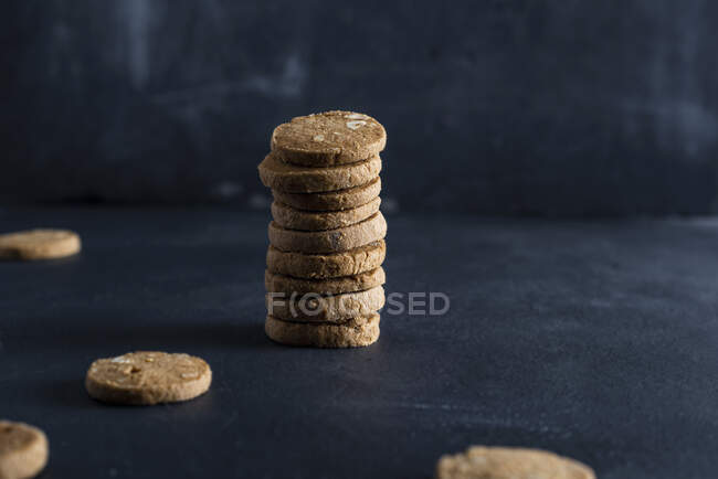 Stack of spelt cookies with nuts against dark background — Stock Photo