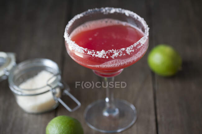 Margarita de melancia em vidro com borda de sal e limas no fundo — Fotografia de Stock
