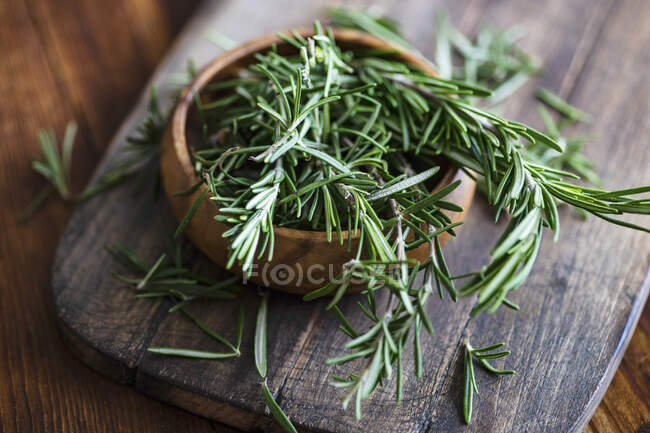 Органическая свежая розмариновая трава на салфетке на деревянном столе — стоковое фото