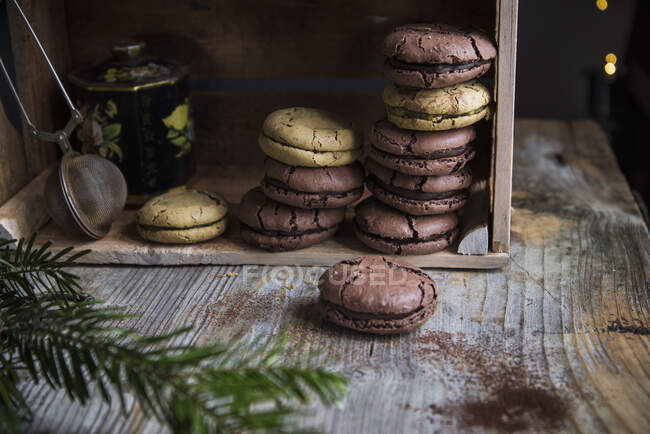 Cracked macaroons in wooden box with tea jar and tea tongs — Stock Photo