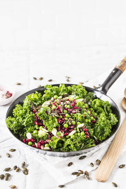 Winter salad with green kale, pomegranate seeds, peas, mozzarella and pumpkin seeds — Stock Photo