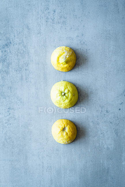 Rangée de trois citrons coupés en deux sur la surface du béton — Photo de stock