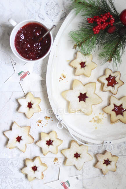 Stars biscuits filled with jam with fir branches and jam jar — Stock Photo