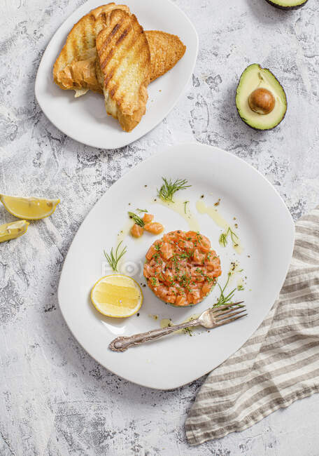 Тартар з лосося подається з підсмаженим хлібом та авокадо — стокове фото