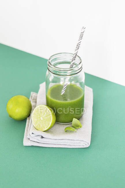Зеленый лайм и базиликовый смузи в стакане с соломинкой — стоковое фото
