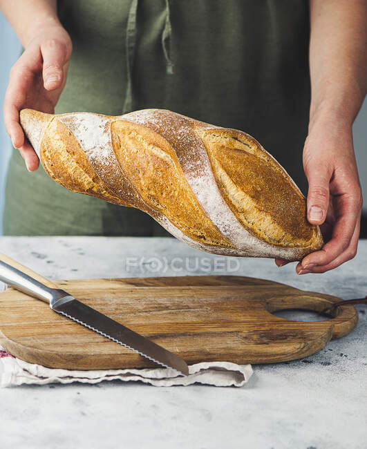 Пекарь держит буханку свежеиспеченного хлеба — стоковое фото