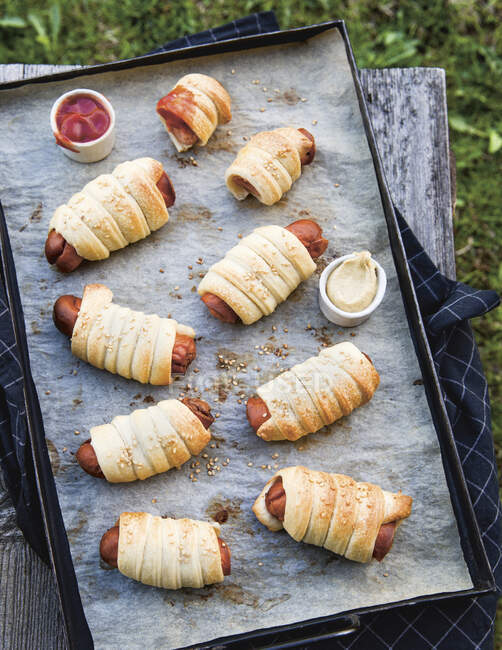Sausages wrapped in pastry on a baking tray - foto de stock