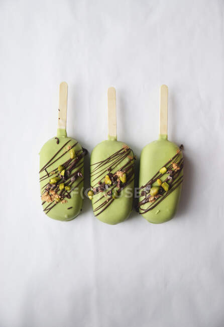 Три зеленых мороженых палочки с фисташковыми орехами — стоковое фото