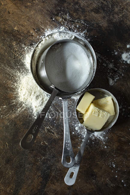 Tasses à mesurer avec farine, sucre et beurre — Photo de stock