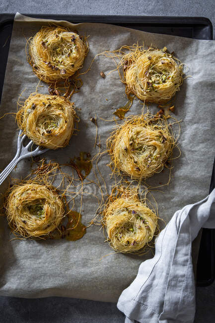 Angel hair pasta nests with pistachios on a baking tray with baking paper and a vintage spatula — Stock Photo