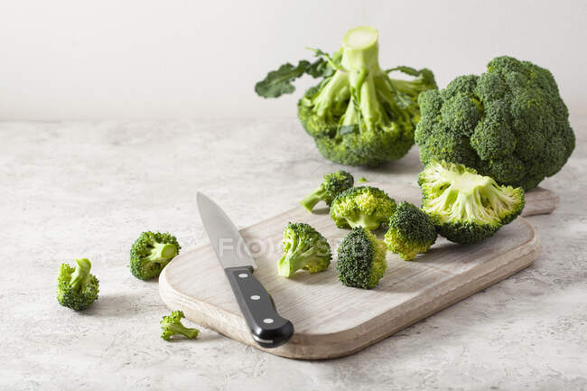 Fresh broccoli with a knife on a wooden chopping board — Stock Photo