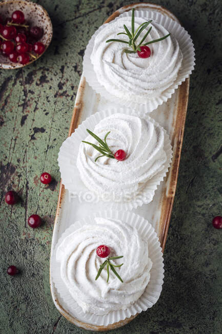 Pasteles de merengue decorados con grosellas rojas y romero - foto de stock