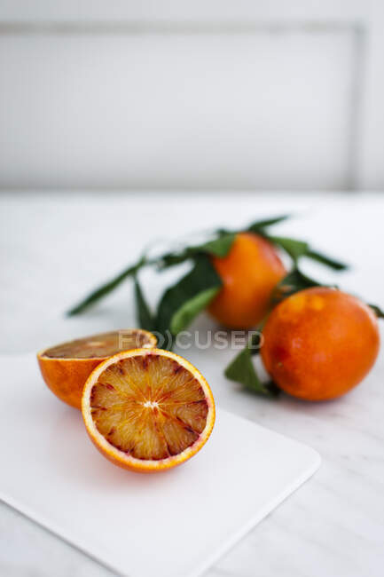 Blood oranges whole and halved on board — Stock Photo