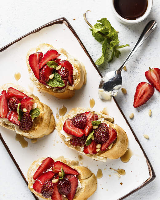 Bruschettas with mascarpone cheese, strawberries, pine nuts and syrup — Stock Photo