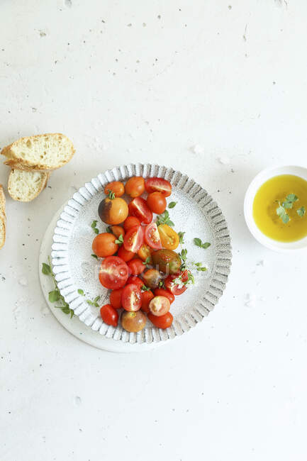 Fresh cherry tomatoes with salt, extra virgin olive oil, fresh oregano and bread — Stock Photo